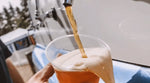 Foamy local draft beer poured from blue mobile bar truck.